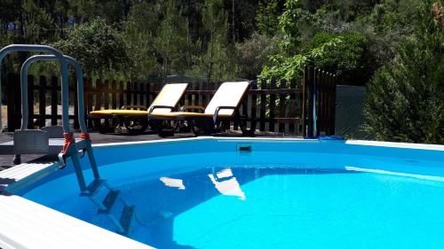 a swimming pool with two chairs and a table at Casinha do Cedro in Baião