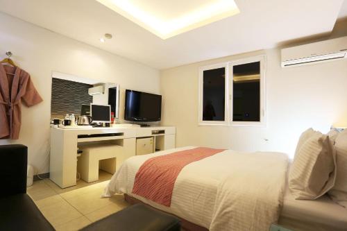 a bedroom with a bed and a desk with a television at Q Hotel in Paju