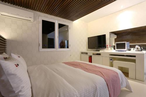 a white bedroom with a bed and a kitchen at Q Hotel in Paju
