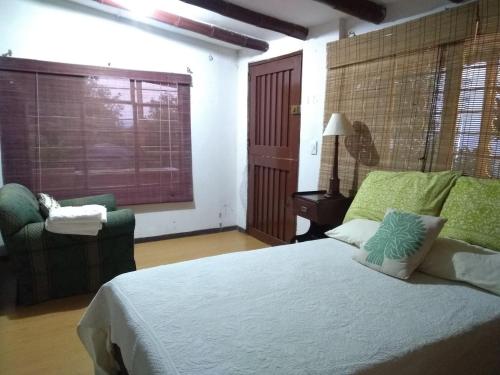 a bedroom with a bed and a chair and a window at Finca Colibrí Zafiro, Altos del Rosario in Cali