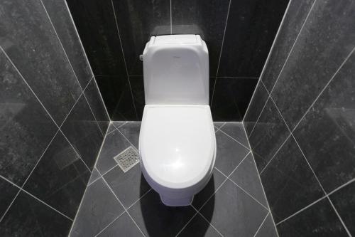 a white toilet in a black tiled bathroom at Q Hotel in Paju