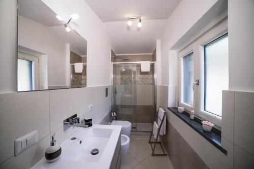 a white bathroom with a sink and a toilet at Villa Bellatrix in Massa Lubrense