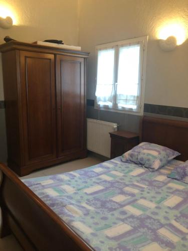 a bedroom with a bed and a cabinet and a window at Maisonnette plein pied - 2km de la mer in Agon-Coutainville