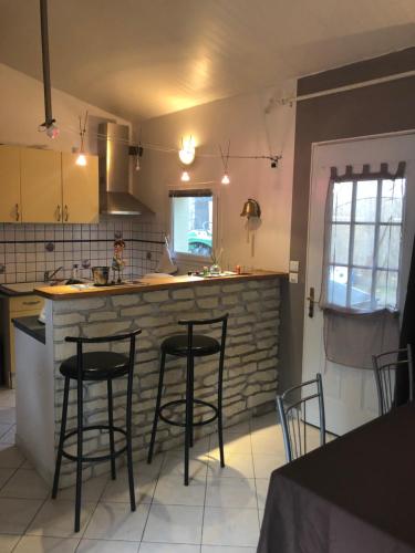 une cuisine avec trois tabourets de bar à un comptoir dans l'établissement Maisonnette plein pied - 2km de la mer, à Agon-Coutainville