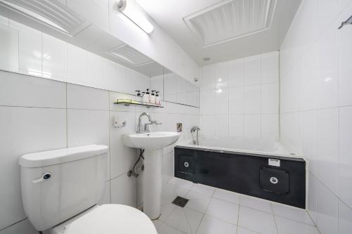 a bathroom with a toilet and a sink and a tub at Q Hotel in Paju