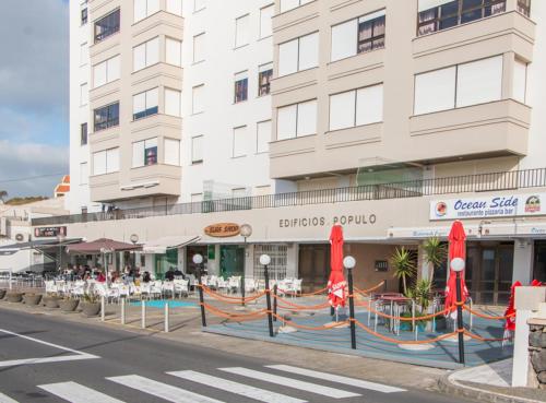 a building with tables and chairs in front of a building at GuestReady - OceanView TopFloor w Terrace in Ponta Delgada