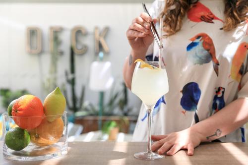 una mujer está de pie en una mesa con una bebida en The Deck Hotel by Happyculture, en Niza