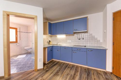 an empty kitchen with blue cabinets and a bathroom at Residence Marteshof in Pfelders