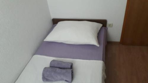- un petit lit avec une couverture violette et des oreillers dans l'établissement Apartment Hrgić Vir, à Vir