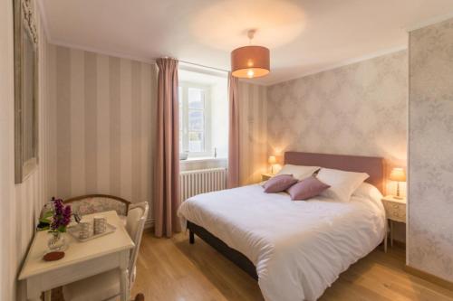 een slaapkamer met een groot wit bed en een tafel bij Le Manoir de Placy - Chambres d'Hôtes in Clécy