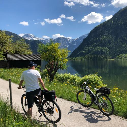 a man riding a bike on a path next to a lake at Landhaus Lilly in Obertraun