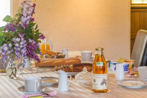 een tafel met een fles wijn en bloemen erop bij Le Manoir de Placy - Chambres d'Hôtes in Clécy