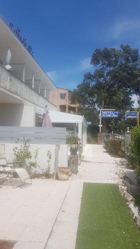 a building with a green lawn in front of it at Hotel Le Golfe Bleu in Cavalaire-sur-Mer