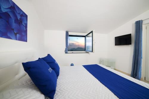 a bedroom with a bed with blue pillows and a mirror at Villa Bellatrix in Massa Lubrense