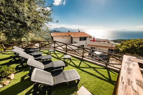 a group of chairs sitting on the grass near the ocean at Villa Bellatrix in Massa Lubrense