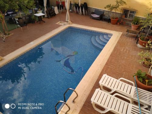 una piscina con 2 sillas blancas al lado en Estudio Rustico, en Tabernas
