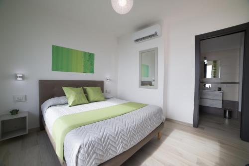 a white bedroom with a bed with green pillows at Villa Bellatrix in Massa Lubrense