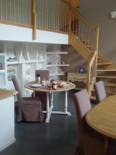 a dining room with a table and chairs and a staircase at L'Heure Bleue gîtes et chambres d'hôtes in Givenchy-en-Gohelle