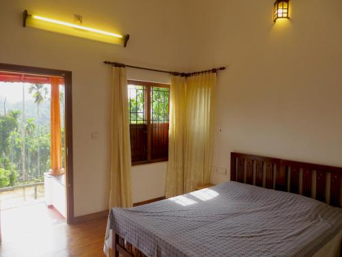 a bedroom with a bed and a large window at Pristine Hills in Meppādi