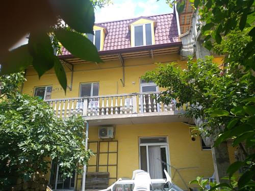 une maison jaune avec un balcon sur le côté. dans l'établissement Why Me Eco-friendly Rooms, à Tbilissi