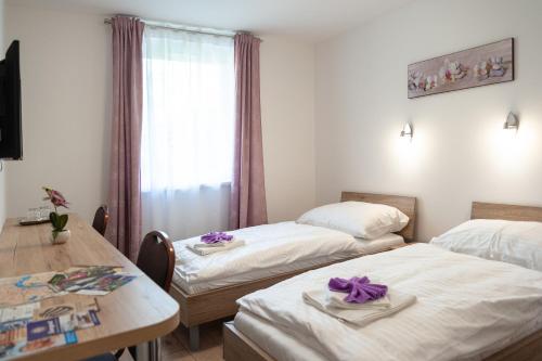 Cette chambre comprend 2 lits, une table et une fenêtre. dans l'établissement Vivien Szálló, à Szeged