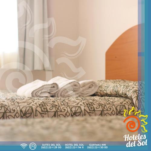 a bed with a pile of towels on it at Suites Del Sol in Guaymas