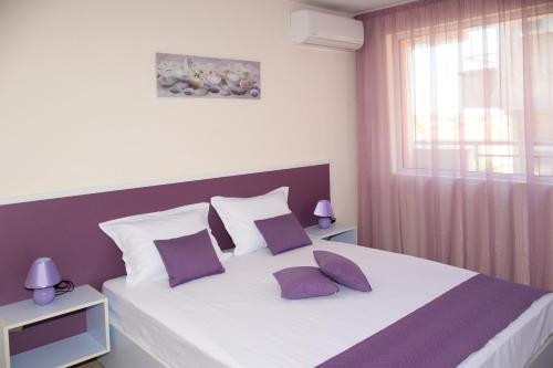 1 dormitorio con 1 cama grande con almohadas moradas y blancas en Rusalka Apart-Residence en Obzor