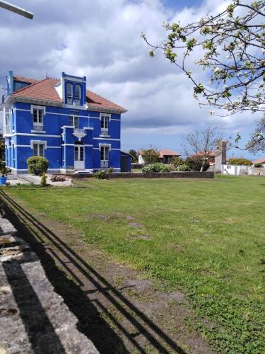 a blue house with a green field in front of it at La Clinica in Ballota