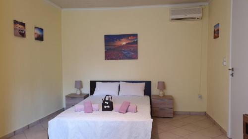 um quarto com uma cama branca e almofadas cor-de-rosa em christos cottage! comfortable and quiet! em Keramoti
