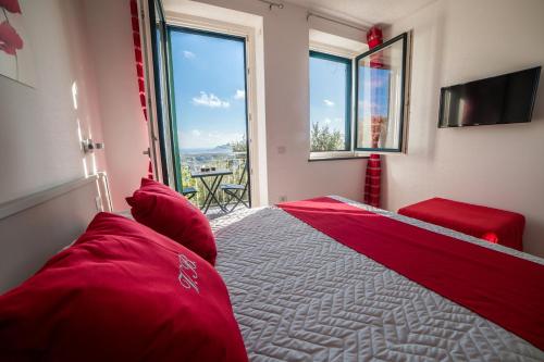 Un dormitorio con una cama con almohadas rojas y una ventana en Villa Bellatrix, en Massa Lubrense