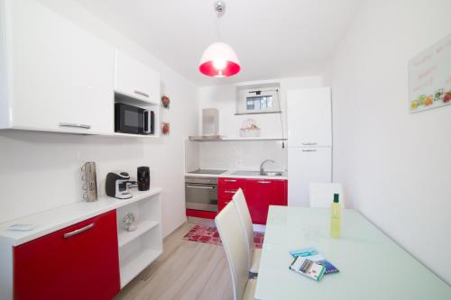 a kitchen with red cabinets and a white table at Villa Bellatrix in Massa Lubrense