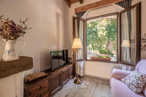 a living room with a tv and a window at El Molino del Corcho in Cazalla de la Sierra