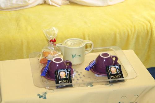 a tray with two cups and a tea set on a table at Au bonheur de LILI in Fontaine-de-Vaucluse