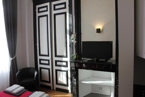 Habitación con puerta, TV y espejo. en Les Cariatides, en Lille