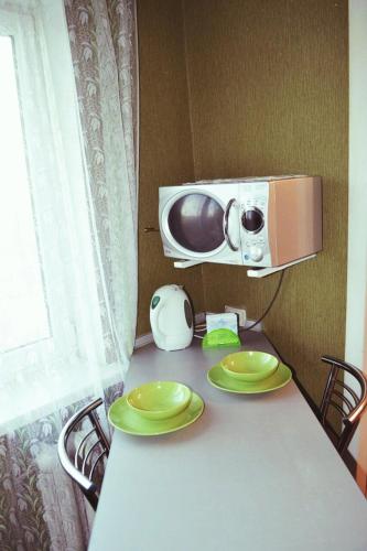 une table avec deux assiettes vertes et un four micro-ondes dans l'établissement Апартаменты в стиле Loft, à Nizhnedneprovsk