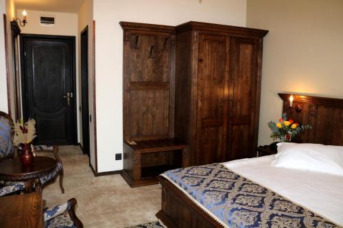 a bedroom with a bed and a wooden cabinet at Castel Transilvania in Baia Mare