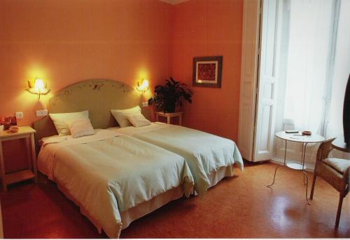 
a hotel room with a bed, chair, lamp and a mirror at Hostal Fornos in Segovia
