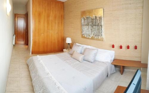 una camera con un letto bianco e una parete in legno di tarragonaapartments Fortuny Reus a Reus