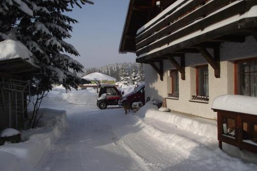 a golf cart parked next to a house in the snow at Pension U Krtka - přímo u sjezdovky in Harrachov