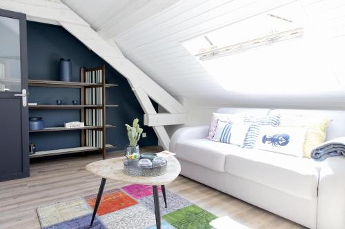 ein Wohnzimmer mit einem weißen Sofa und einem Tisch in der Unterkunft Une Odeur de Tilleul in Montbrison
