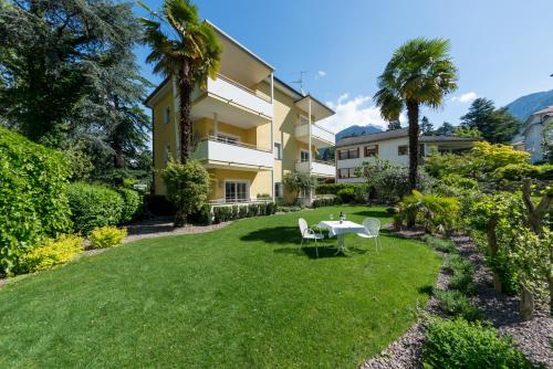 - un jardin avec une table et des chaises en face d'un bâtiment dans l'établissement Villa Majense, à Merano