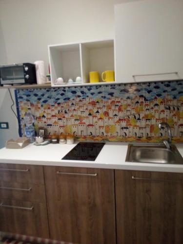 a kitchen with a sink and a tile wall at Case Vacanza Le Casette in Santo Stefano di Camastra