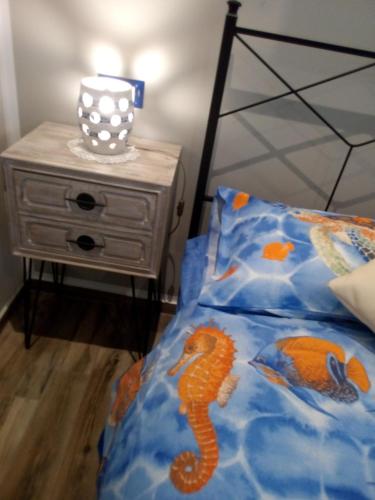 a bed with a blue comforter and a table with a nightstand at Case Vacanza Le Casette in Santo Stefano di Camastra