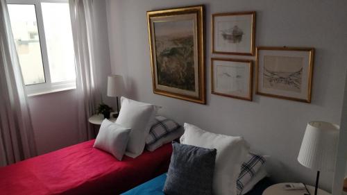 a bedroom with a red bed with pillows and pictures on the wall at Little Blue House in Marsalforn