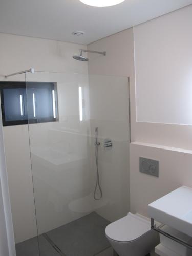 a white bathroom with a shower and a toilet at Canto do Nemo in Canto da Areia