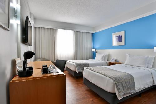 Una habitación de hotel con dos camas y un televisor. en Slaviero São Paulo Downtown, en São Paulo