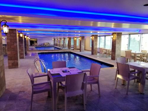 a restaurant with a pool with tables and chairs at Seven Days Hotel in Irbid