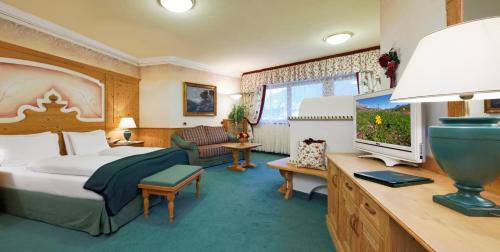 a bedroom with a bed and a tv in a room at Hotel Sassongher in Corvara in Badia
