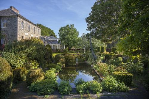 a garden with a pond in front of a building at Kilmokea Coach House in New Ross