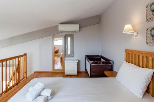 a bedroom with a large white bed and a chair at Mythos Suites Diskos in Léntas